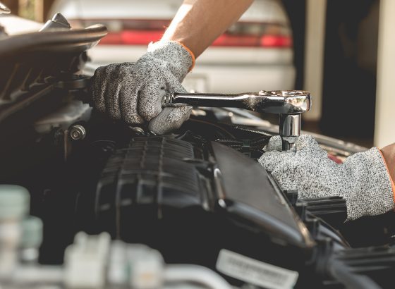 Automobile mechanic repairman hands repairing a car engine automotive workshop with a wrench, car service and maintenance